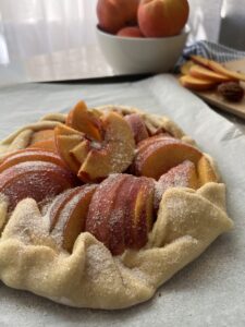 Peach galette topped with sugar pre-baked